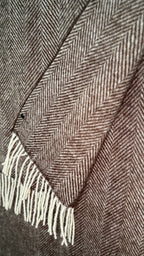 Close-up of a brown and beige herringbone patterned fabric with white fringe.